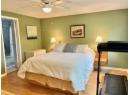 Bedroom with light wood-type flooring, a ceiling fan, ensuite bath, and a textured ceiling