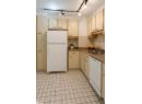 Kitchen featuring white appliances, cream cabinetry, backsplash, and light tile patterned floors