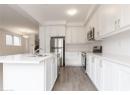 Kitchen featuring stainless steel appliances, light stone countertops, light wood-style flooring, white cabinets, and a kitchen island with sink