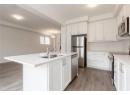 Kitchen featuring stainless steel appliances, white cabinetry, a kitchen island with sink, and light wood-style flooring