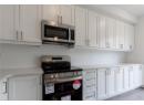 Kitchen featuring stainless steel appliances, white cabinets, and light stone counters