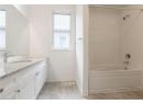 Full bath featuring bathing tub / shower combination, vanity, and light wood-type flooring