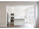 Kitchen with a kitchen breakfast bar, light countertops, appliances with stainless steel finishes, white cabinets, and dark wood finished floors