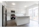 Kitchen with stainless steel appliances, white cabinetry, dark wood-type flooring, and a center island with sink