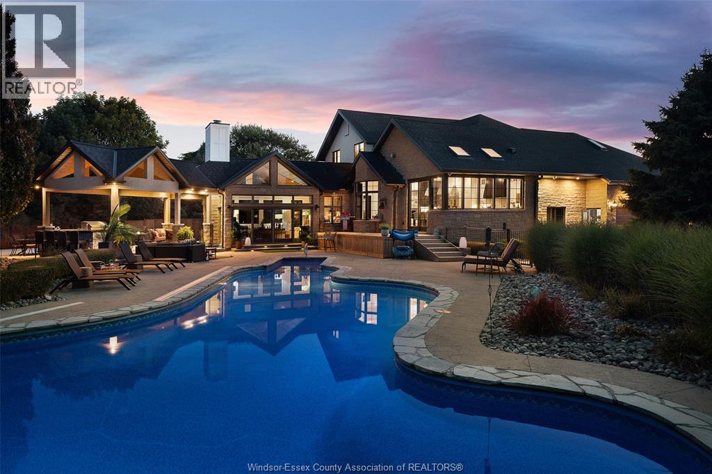 A rare offering — this exquisite custom-built estate with approx 7,500 sq ft is perfectly set on 3+acres of manicured grounds just minutes from charming downtown Kingsville. Every detail is designed for elevated living and effortless entertaining. It features 5 bedrooms, 4.5 baths, 7 fireplaces, soaring 10 ft ceilings, and a stunning full walkout lower level opening to an English sunken garden. This home is complemented with an in-law suite and premium finishes throughout. This smart home has an integrated sound system, automated blinds, and heated floors. Relax in your private retreat with the inground pool, hot tub, and covered lanai, cozy up by the natural fireplace. The tranquil pond and private island offers hammock time or camping for the kids. Chef’s dream kitchen with 14ft Cambria island, walk- in pantry, professional appliances and a dumb-waiter for serving in the lower level. It is flooded with natural light and anchors the home. Primary bedroom features a walk-in closet and a bank of custom cabinetry, en-suite bath and Juliette balcony overlooking mature trees. 3 bedrooms grace the upper floor and lead to the separate in-law suite with lounge and kitchenette area with dedicated entrance. The heated pole barn with separate drive completes this truly exceptional property — a rare fusion of luxury, lifestyle, and location. (id:48254)