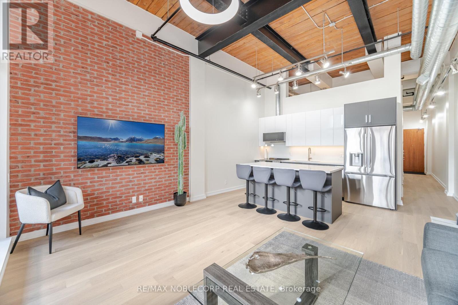Welcome to one of the most impressive lofts in the city, located in one of its most sought-after buildings! Be the first to enjoy this brand new unit - extensively renovated to the nines and never lived in! This rare, sunny, south-facing hard loft features a large original brick private terrace. The ground floor location offers a beautiful view backing onto the quiet, gated private courtyard. Soaring 13 ft. wood beam ceilings and exposed red brick create the perfect blend of old industrial charm and modern, sleek, high-end finishes. Enjoy easy, elevator-free access with prime ground floor parking and a locker literally just steps from the unit - living here truly feels more like a house. This loft has undergone a complete high- end renovation with the highest quality materials: brand new hardwood flooring, a stunning new bathroom with large porcelain tiles, heated floors, an oversized soaker tub, and premium vanities. The brand new two-tone kitchen features a custom glass backsplash and over $10K spent on top-of-the-line appliances. The exposed brick wall in the living area gives this unit a true "wow" factor - a special, unique space that shows 10/10! This unit is ideally situated on the south side of the building and is one of the few with outdoor space offering this desirable exposure. No need to worry about future condos being built in front of you! The building is exceptionally well-managed with low maintenance fees. Enjoy a convenient 5-minute walk to Exhibition GO Station with easy access to Union Station in just 8 minutes. A future subway station and a large park are also being developed right across the street. (id:48254)