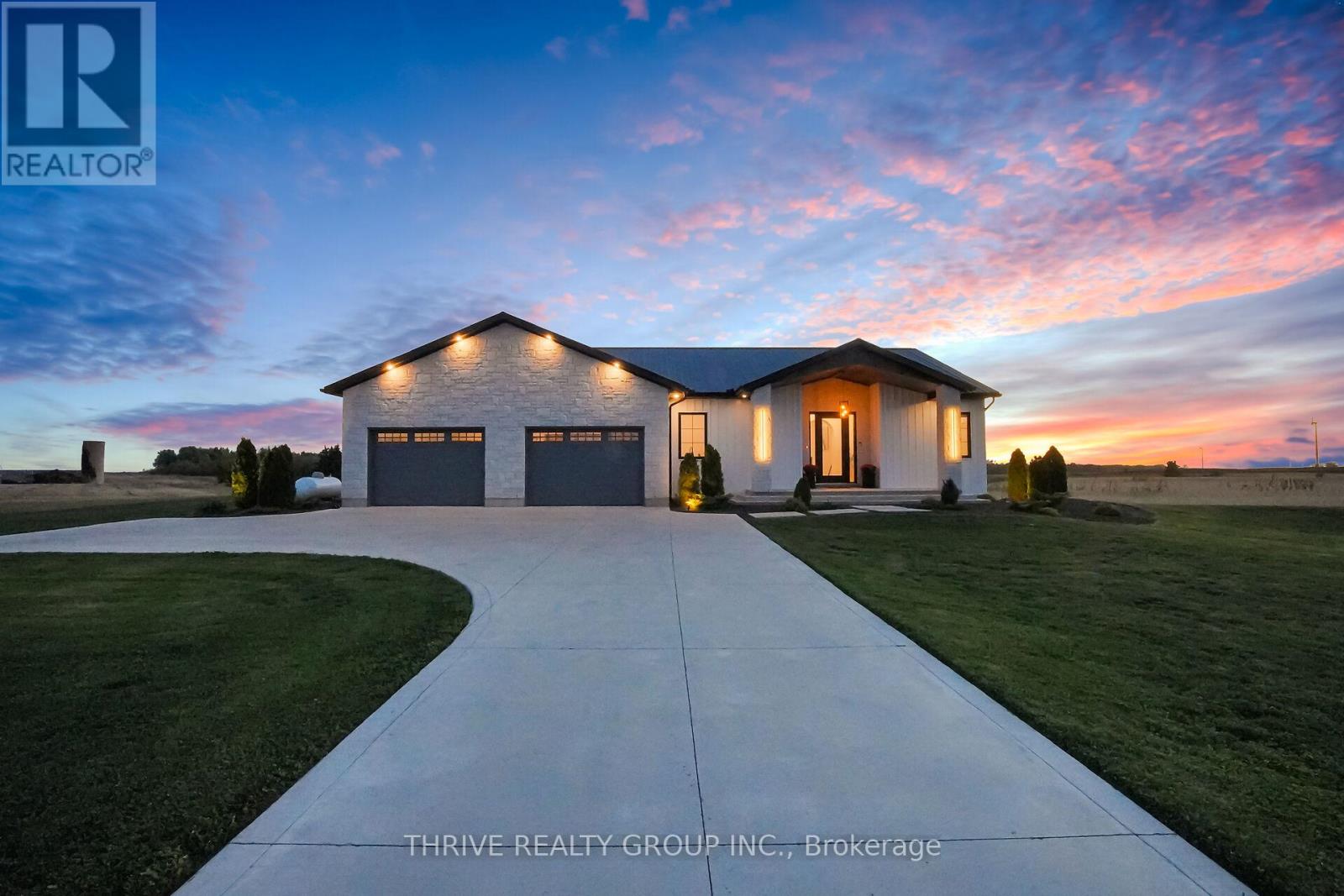Constructed in 2023 on a 1.05 acre parcel of land surrounded by fields & seclusion, 25451 Wood Rd is the perfect rural destination. As you pull off of the paved road into the poured concrete laneway, you are greeted by the sound of the fountain circulating water through the stone lined pond. The oversized insulated 2-car garage includes 12' wide overhead doors, recessed lighting, & waterproof wall panelling. Entering the home, you are greeted with a tiled foyer & mudroom with 10' ceilings that span the entirety of the main floor. The main floor living space begins with the kitchen, equipped with quartz countertops, stainless steel appliances, & an 8' island with waterfall countertops. Just off the kitchen is the dining room & family room including a tiled entertainment area & fireplace as well as uninterrupted views of the country side. The main floor primary suite boasts a 4-piece ensuite with a 4'x8' custom shower & walk-in closet with beauty station & laundry chute. Heading into the basement with 9' ceilings, you are introduced to the lower level living room containing another custom entertainment area and fireplace. The lower level houses 3 additional rooms, a 4-piece bathroom, laundry room, & the utility room. Upon returning upstairs, you are transported to a luxurious outdoor covered patio incorporating a 13' swim spa, fireplace, tv, concrete island, stone barbecue enclosure, recessed lighting, built in sound system, & beautiful country views. Continuing into the backyard, you are presented with a chicken coop, garden area, & a stone retaining wall shaping the sunken seating area & fire pit. Also included on the property is a steel roof, Generac generator (supplying the entire living area & sump pump), automatic exterior lights, drive way indicator, a 200-amp panel with 100-amp sub-panel & surge protector, as well as permit approval for a 35' x 35' detached shop. (id:48254)