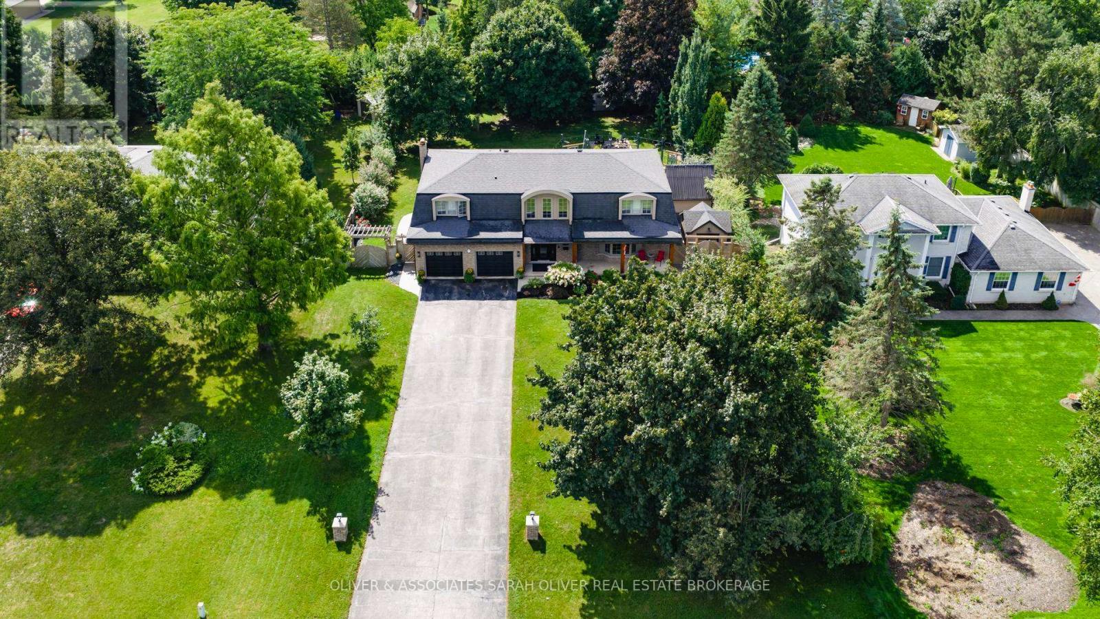 Set on a beautifully treed half-acre lot in an exclusive small community setting, this exceptional two-storey residence offers the perfect balance of privacy, luxury, and convenience. Surrounded by mature trees and lush landscaping, the backyard feels like a private resort - complete with an inground pool, expansive entertaining space, pool house and covered patio.  Peaceful seclusion rarely found so close to the city. Inside, the home features four generous bedrooms and thoughtfully updated living spaces designed for both everyday comfort and elegant entertaining. The gourmet kitchen is beautifully appointed with quality cabinetry, premium finishes, and large windows overlooking the private grounds. Updated bathrooms offer spa-inspired finishes and timeless sophistication. The fully finished lower level adds incredible versatility and includes a convenient walk-up to the backyard. This would be ideal for extended family living, guests, or seamless indoor-outdoor entertaining. Expansive windows throughout flood the home with natural light, enhancing its airy, upscale feel. This is a rare opportunity to enjoy estate-style living on a half acre, with resort-like amenities, in a welcoming community just moments from shopping, major highways and premier golf destinations. (id:48254)