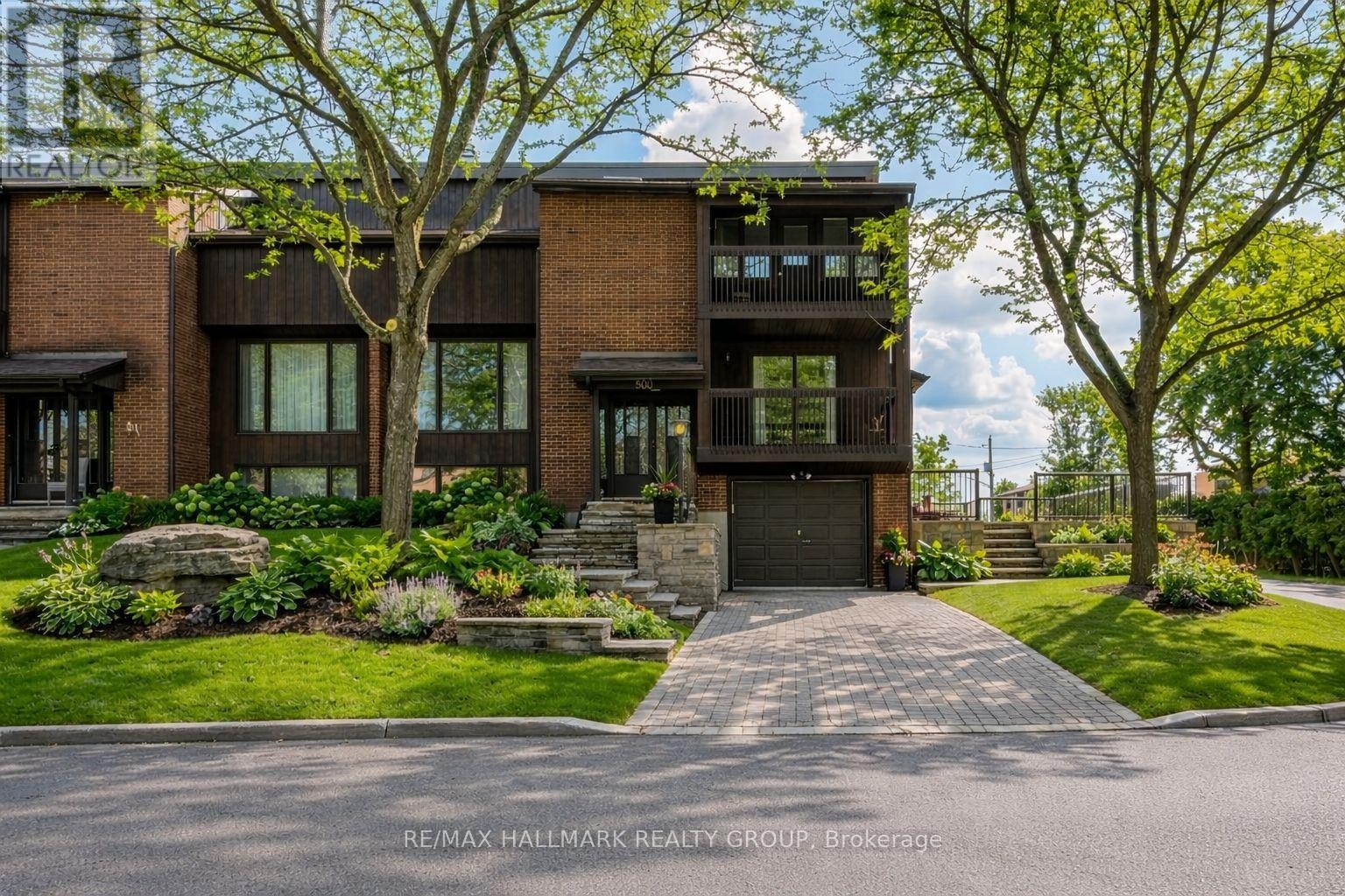 A rare mid-century architectural gem offering nearly 3,000 sq ft of living space, this sun-filled home stands out with its soaring ceilings, extensive stonework, and custom wood detailing throughout. Designed with a distinctive multi-level layout, the main living area features vaulted ceilings, skylights, and expansive windows that flood the space with natural light. A second, more intimate living room with its own wood-burning fireplace provides a cozy retreat, while the primary living space is ideal for entertaining.The dining room opens onto a balcony with views of the Gatineau Hills, creating a seamless indoor-outdoor experience. The kitchen connects easily to the main living spaces and eating area for everyday functionality. This home offers four bedrooms, including three on the upper level and a fourth bedroom on the main floor, ideal for guests or a home office. The primary suite features high ceilings, a custom walk-in closet, private ensuite, and its own balcony overlooking the hills. A convenient second-floor laundry room adds to the thoughtful layout.Custom woodwork enhances the warmth and character throughout. The finished lower level includes a bright rec room with large eye-level windows and plenty of storage space.Set on a premium corner lot, the home showcases extensive, recently completed stonework, including a beautifully designed interlock driveway with side-by-side parking and fully interlocked side grounds that enhance both function and curb appeal. Major mechanical updates include a high-efficiency furnace, central A/C, and a recently updated roof, offering peace of mind for years to come. A tandem garage with direct lower-level access completes this truly unique offering, finished with high-end aluminum-clad windows throughout and over $100,000 invested in exterior stonework.Furnace & AC 2021 (id:48254)