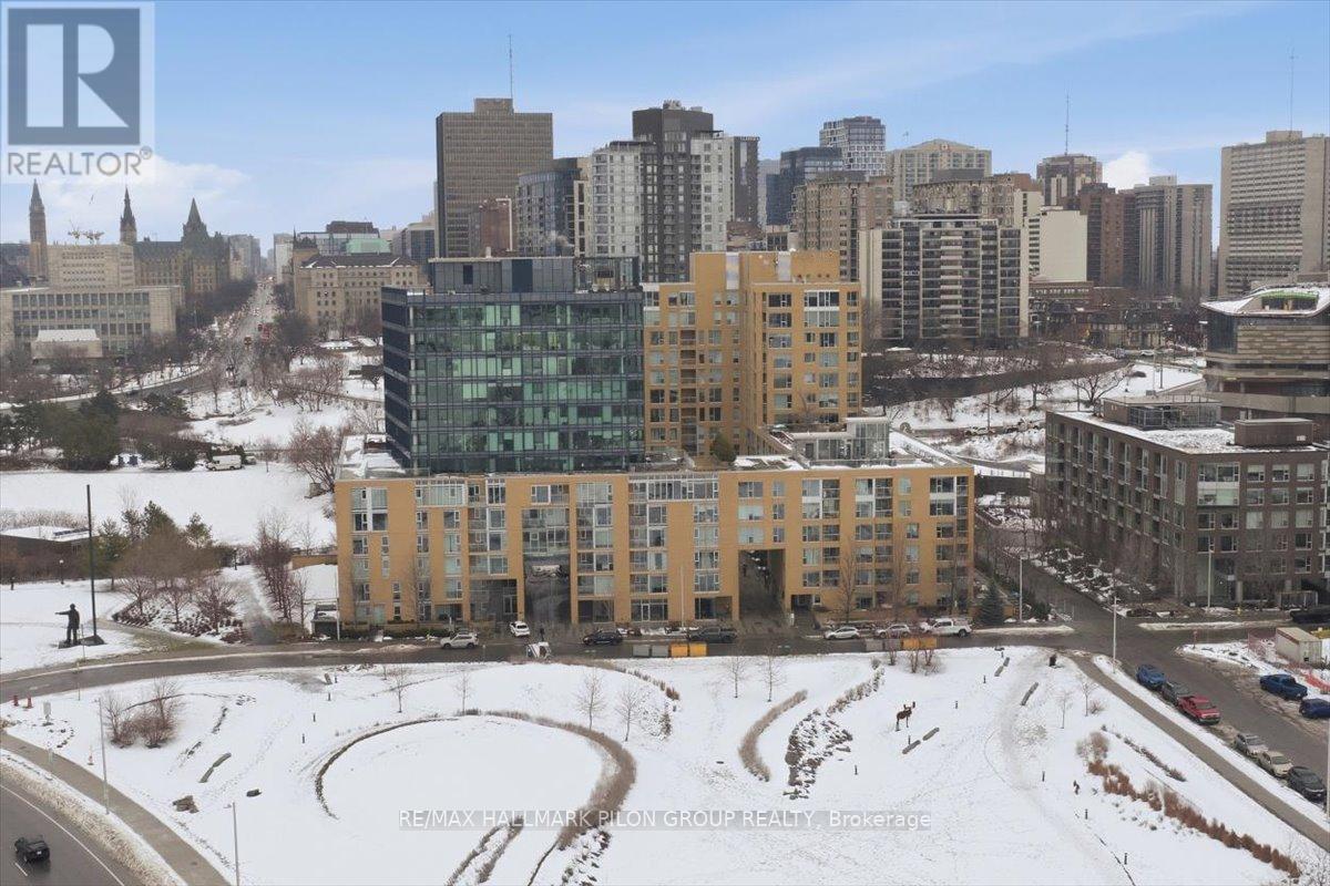 Experience elevated city living at 250 Lett Street, a rarely available corner-unit condo in the heart of LeBreton Flats that perfectly blends urban energy w/peaceful surroundings. This modern 2-bed, 2-bath residence offers underground parking, private storage locker, & in-unit laundry, delivering both comfort convenience. Inside, the home is bright, stylish, & move-in ready. Upgraded hardwood flooring flows throughout, complemented by granite countertops, custom window coverings, & fresh paint for a clean, contemporary feel. The thoughtfully designed layout includes a spacious primary bedroom w/double-vanity ensuite, while floor-to-ceiling windows flood the space w/natural light. One of the standout features of this condo is its south-west exposure, offering sweeping, unobstructed views that are truly timeless. Overlooking the Ottawa River & LeBreton Flats, the scenery changes beautifully with the seasons, & the sunsets are exceptional. You'll also enjoy a direct view of the annual Bluesfest festival hosted at the Canadian War Museum - no tickets required. Take in live performances from your private balcony or head to the rooftop terrace for your own VIP viewing experience. Located directly along the Capital Pathway, this home is ideal for those who love walking, cycling, or being close to nature while remaining steps from the city core. The nearby Pimisi LRT station provides effortless access to downtown, while vibrant neighbourhoods such as Chinatown, Little Italy, Sparks Street, & Gatineau are all within easy reach. The building is highly efficient & LEED certified, offering an impressive suite of amenities including a rooftop terrace with BBQs, a heated outdoor pool, a fully equipped gym, & a party room for entertaining. With exciting future development planned for the area, this location offers both lifestyle appeal & long-term value. A rare opportunity to secure a turnkey condo with iconic views, premium amenities, and one of Ottawa's most dynamic locations. (id:48254)