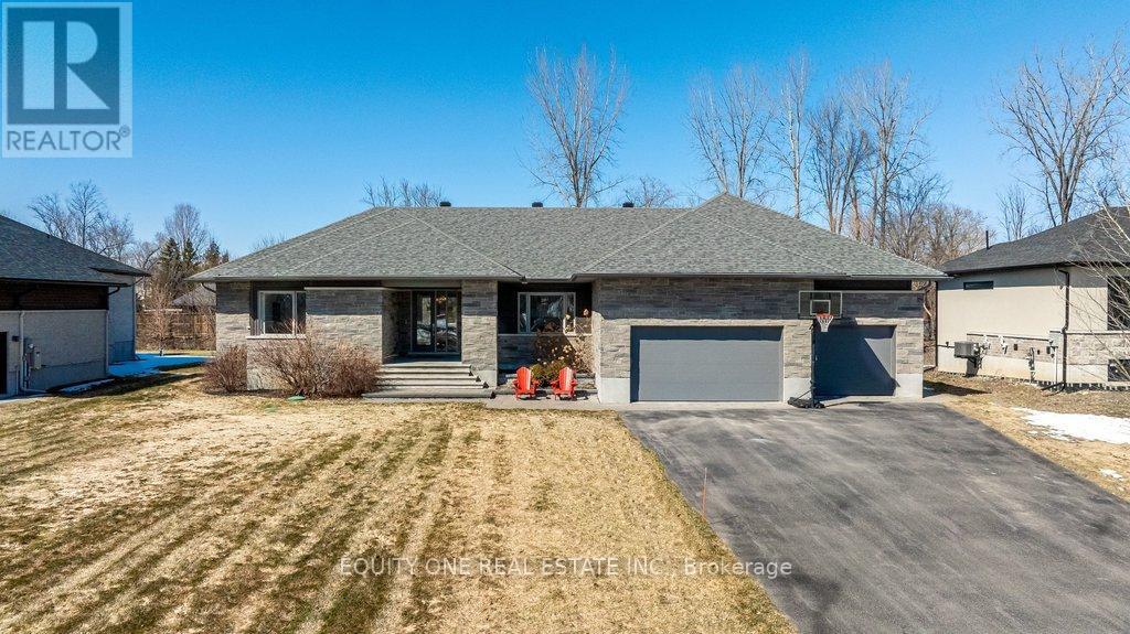 Welcome to this spectacular 4+1 bedroom, 4 bathroom bungalow in the highly sought-after Lakewood Trails community of Greely where modern luxury meets peaceful estate living. Built by Mackie Homes, this beautifully designed residence offers exceptional craftsmanship, thoughtful upgrades, and an ideal layout. The main level features a bright, open-concept design anchored by a stunning great room with a cozy natural gas fireplace, seamlessly flowing into a designer kitchen with quality cabinetry, stone countertops, and generous prep space ~ perfect for hosting family and friends. Designed for privacy, the primary suite is set on one side of the home, offering a peaceful retreat complete with his & hers walk-in closets and a luxurious ensuite featuring a freestanding soaker tub, glass shower, and heated floors. On the opposite side of the home, you'll find three additional well-sized bedrooms and a full bathroom-ideal for family living or guests. A spacious mudroom with built-in cabinetry provides excellent everyday storage and organization, while the main floor laundry room adds convenience and functionality.The fully finished lower level expands your living space with a large recreation area, dedicated exercise space, additional bedroom, and full bathroom. A separate theatre room with a second gas fireplace creates the perfect setting for movie nights and entertaining ~ ideal for multi-generational living or a private retreat. Car enthusiasts and families alike will appreciate the heated oversized 3-car garage, complete with built-in shelving for storage and direct access to the basement ~ an incredibly practical feature. Storage is abundant throughout the home, making it easy to stay organized and clutter-free. Outside, enjoy a beautifully landscaped backyard, rear patio, and upgraded exterior featuring stone and brick finishes, all set within one of Greely's most desirable communities featuring a community rec centre, pool and gym. Association fee of $350/year. (id:48254)