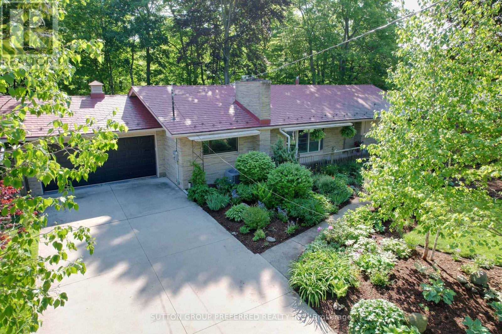 Nestled in the executive area of the Sherwood Forest neighbourhood, this distinctive stone-faced home offers a rare blend of country charm and modern comfort. Set on a beautifully landscaped 100-foot lot backing onto a serene wooded ravine, this 5-bedroom, 4-bathroom residence is perfectly suited for families and avid entertainers alike, with over $150,000 in recent renovations and upgrades.The main level showcases original oak hardwood flooring and features a spacious living room with a gas fireplace, formal dining room, and a warm family room with a second fireplace, seamlessly open to the kitchen. A sun-filled sunroom with skylights and stunning 180-degree ravine views provides a tranquil space to relax year-round. Two bedrooms are located on this level, including the primary suite. Many windows are equipped with exterior insulated roll shutters for added comfort and efficiency. The fully renovated lower level (2022) offers exceptional additional living space, featuring three generous bedrooms, a stylish 4-piece bathroom, and a large recreation room with a third fireplace. Extensive upgrades include updated insulation, new windows, professional waterproofing, and a new sump pump. Outdoor living is equally impressive, with a spacious 32-foot deck overlooking the ravine and a 40-jet Hydro hot tub-ideal for unwinding or entertaining. Additional highlights include a lifetime-warrantied interlocking metal roof, reclaimed heritage pine woodwork throughout, and an oversized double garage complete with workshop. Located just minutes from Western University, Medway Valley Trails, parks, and top-rated schools, this exceptional home offers a perfect balance of nature, luxury, and everyday convenience. (id:48254)