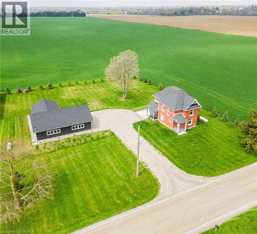 Fall in love with this classic red brick farmhouse that truly has it all! Just 2 minutes outside the peaceful village of Thorndale and only 10 minutes from London, it's the ideal spot to embrace your dream of country living. Nestled on over 1 acre, there's plenty of outdoor space to enjoy, yet it's still easy to maintain. Extensive renovations have brought modern comforts while preserving the timeless charm of this century home. The main floor offers a seamless flow between rooms, with natural light filling the space and creating a welcoming atmosphere. The mudroom has plenty of storage for shoes and coats, plus a space designed with your furry friends in mind. The kitchen boasts generous counter and cupboard space, with an island and warm wood cabinetry, complemented by a light countertop and crisp white backsplash. The walk-in pantry adds extra storage for small appliances, dry goods, cleaning supplies, and more, keeping the kitchen tidy and organized. The living room opens into the dining room, with a convenient powder room and main floor laundry nearby. A cozy den, just off the front door, offers a versatile space with many possibilities. The primary bedroom contains a private ensuite with double sinks and a walk-in shower. Three additional spacious bedrooms provide room for your family, and the 4 piece bathroom includes a shower/tub combo and built-in shelving for linens. The fully insulated 2000 sq ft garage/workshop is a standout feature, with radiant in-floor heating - separately zoned between the shop and gym, cathedral ceilings with 9-foot walls, a generator plug with an automatic switchboard for a standby system, CAT6 wiring, plumbing roughed in for a septic tank and bathroom, and conduit for water to be run from the well in the house. Imagine the joy of sitting outdoors on the concrete patio in warm summer months, surrounded by peaceful fields, listening to the crickets hum - make this dream your new reality! (id:48254)