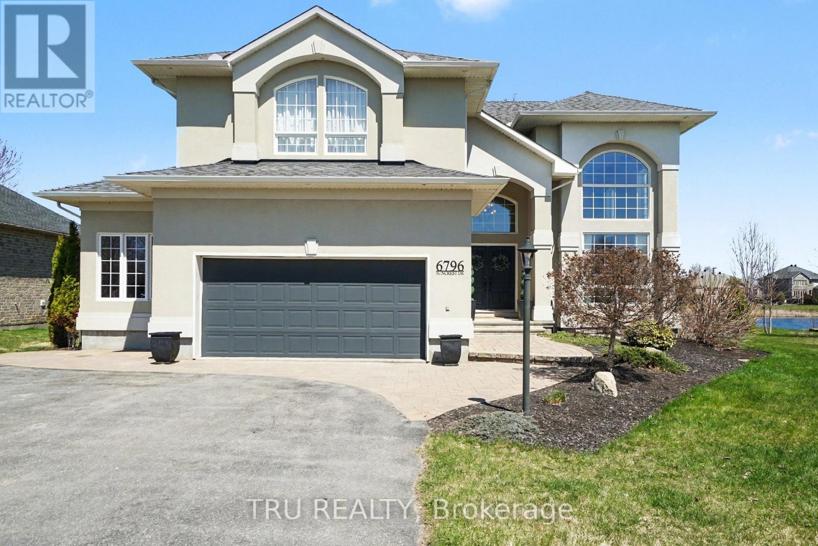 Experience refined WATERFRONT living in this stunning 4+1 bedroom home on Southwood Lake in the coveted Woodstream community. Bathed in natural light, the home's foyer welcomes you with 18' vaulted ceilings that flow seamlessly into an elegant living room, where a dramatic picture window and rich hardwood floors extend throughout the main level. A formal dining room-currently styled as an office-comfortably hosts up to 10 guests and features custom built-in shelving with chic barn doors. The chef-inspired eat-in kitchen offers granite countertops, stainless steel appliances including a beverage centre, under-cabinet lighting, and a bright solarium-style breakfast area with water views and walkout to a composite, two-tier deck. The family room features large windows, providing tranquil lake views and a gas fireplace with stone surround. A main-floor bedroom/den with cheater access to a full bath provides flexibility for guests, multigenerational living, or a private workspace. A mudroom with laundry and direct garage access adds everyday convenience. The hardwood staircase leads to the second floor with a luxurious primary suite featuring a lakeside sitting area, a custom walk-in wardrobe, and a double-sided fireplace shared with the 5-piece ensuite with soaker tub, double vanity, and separate shower. There are two additional bedrooms, one with cathedral ceilings, and EACH HAVE THEIR OWN PRIVATE ENSUITE BATHROOM. The finished lower level offers a spacious recreation/games room, pantry/wine room, fifth bedroom, and abundant storage. Outdoors, a beautifully landscaped lot with bonfire area, irrigation system and a treehouse invite lakeside living- waterskiing, boating, fishing, and skating/hockey in winter. Inviting community association provides use of a private community centre, saltwater pool, tennis and basketball courts, and a gym (annual fee $450), walking/biking paths, and year-round events. 24hrs irrevocable on all offers. (id:48254)