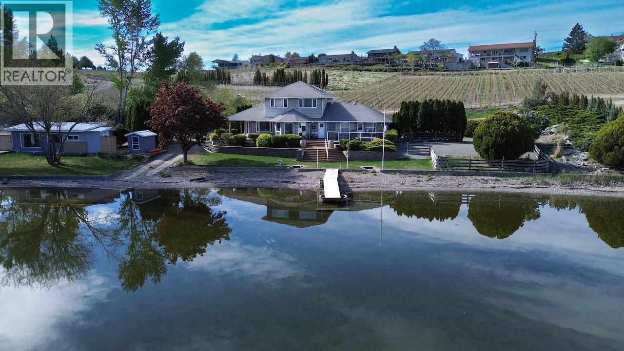 Rare lifestyle and investment opportunity on the shores of Osoyoos Lake. This 2.3-acre parcel is fully exempt from the ALR and serviced by municipal water and sewer—an uncommon and highly desirable combination for waterfront properties of this scale. The property measures approximately 550 feet of private, north-facing shoreline, complete with a registered boat dock and private concrete boat launch. This unique orientation captures exceptional, unobstructed lake views rarely found in the South Okanagan. Built in 1994, the 2,600 sq.ft. main residence offers 5 bedrooms and 3 bathrooms, highlighted by a spacious north-facing patio overlooking the water. The primary suite is located on the main level, with additional guest and family accommodations above. Expansive windows throughout the home showcase the lake as a natural focal point. A separate 700 sq.ft. updated cottage is fully serviced, including natural gas, offering flexibility for extended family use or rental income potential. Surrounded by vineyards yet free from ALR restrictions, this property presents a compelling long-term opportunity. Its size, servicing, and premier waterfront location support strong potential for future subdivision or further development (subject to approvals), while also serving as an ideal legacy property or private retreat. Bonus 25' x 24' insulated detached workshop/garage. Come home to Canada’s most sought-after waterfront settings in Canada's only Desert, Osoyoos BC (id:48254)