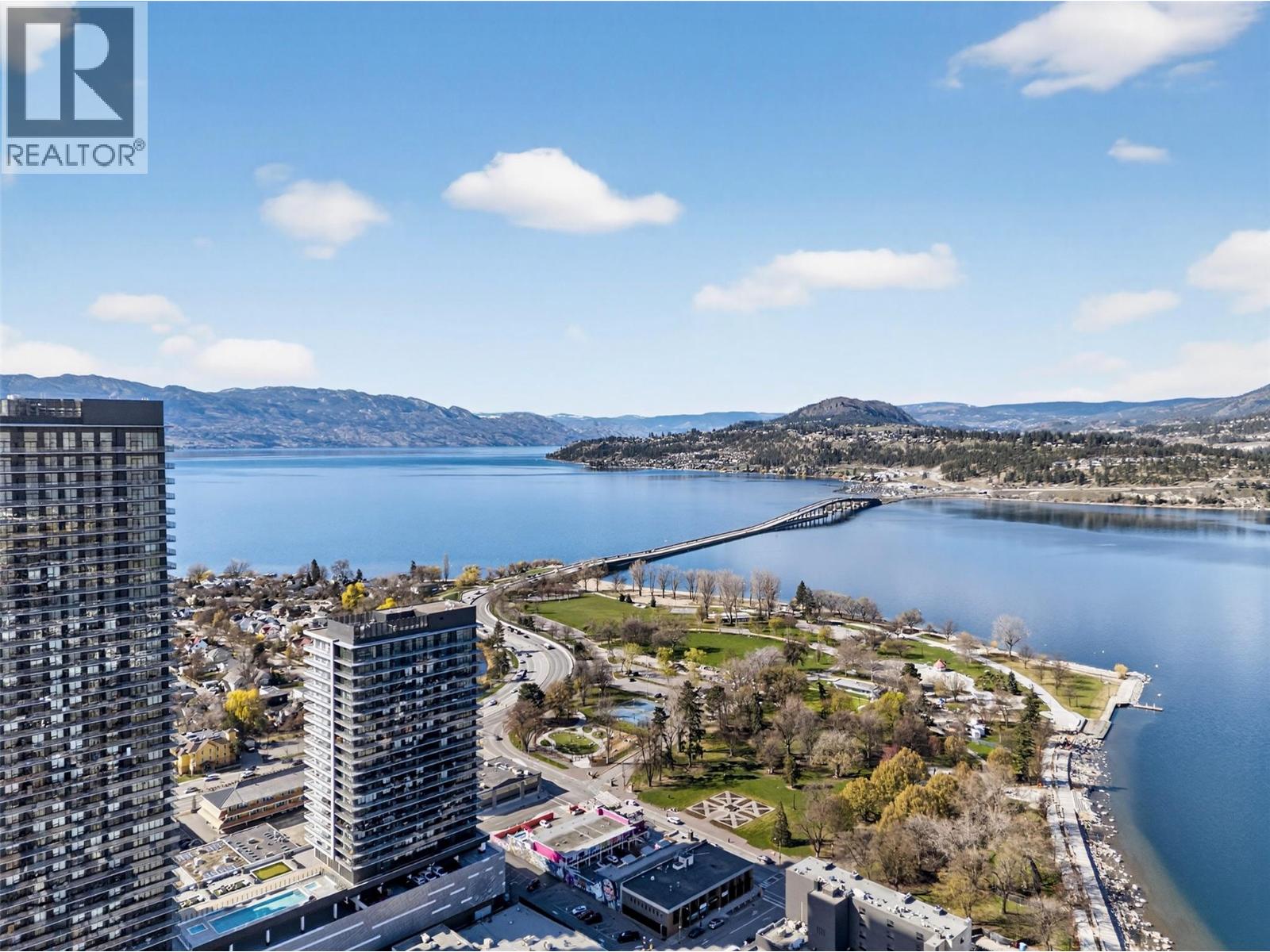Stunning 2025, 3 bedroom + den condo in the heart of downtown Kelowna. This is a large corner unit with breathtaking views of Okanagan Lake, City Park, Kelowna Yacht Club, Bennett Bridge, as well as sparkling city lights on both sides of the lake. Located on the quiet side of the building (NW corner) and has an excellent split-plan layout & has lots of upgrades which include beverage center, entertainment center, closet & storage improvements, etc. It also has a panoramic wraparound balcony, c/w natural gas BBQ hookup. All rooms have spectacular views; currently, the 2nd bedroom is set up as a guest room, the 3rd bedroom is set up as an office with its own private balcony & the den is set up as an additional bedroom-lots of flexibility with basically 4 bedrooms.  All rooms have TV's and mounts. The living room features a built-in 75"" TV & 72"" electric fireplace. Resort-like amenities include large outdoor pool, hot-tubs, games rm, golf simulator, putting green, sauna, steam, dog run & wash, hobby rm, party rooms & more. This is an exceptional condo and the location is 2nd to none - short walk to shops, restaurants, Safeway, coffee shops, lakefront boardwalk, water sports rental facilities, the community theater, Prospera Place & City Park which gives immediate access to tennis courts, lovely beach, walking & bike trails, dog park & more. Includes 2 side-by-side, heated, indoor parking stalls in a premium location, storage locker & secure bike storage. Turnkey option available (id:48254)