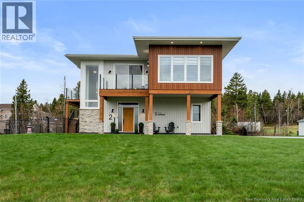 Welcome to 21 Allée Alyre in Bouctouche, a stunning contemporary-style home built in 2021 and set on a beautifully landscaped 1-acre lot with breathtaking unobstructed WATER VIEWS! Stamped concrete walkways and patio areas wrap from the front entrance around the sides of the home, adding to its impressive curb appeal. The main floor features a bright foyer, a combined laundry and 2-piece bath with industrial-style sink, built-in storage, and hanging space, along with a spacious bedroom. Upstairs, 9-foot ceilings throughout and a cathedral ceiling in the living room enhance the open-concept layout filled with natural light from expansive windows and two sets of patio doors overlooking the water. The living room features a shiplap electric fireplace with a rustic wood mantle and opens to a shared balcony with the 4-season sunroom. The sunroom includes its own electric fireplace and convenient office nook. The modern kitchen offers ceiling-height white cabinetry, granite countertops, stainless steel appliances, farmhouse sink, and a large island with breakfast bar. The dining area is surrounded by windows showcasing the breathtaking views. The primary suite features a walk-in closet and mini split, while the luxurious 4-piece bath includes granite countertops, dual sinks, and a tiled glass shower with rain showerhead, detachable wand, niches, and a large feature window. A third bedroom completes this level. The heated attached double garage offers epoxy floors, mini split, built-in bar, screened overhead doors for the summer, and an additional 7x7 side overhead door for added convenience. Outside, enjoy the fenced backyard with a two-tier deck, baby barn, stone fire pit, and incredible scenery. A rare opportunity to own a modern, move-in-ready home with breathtaking water views in one of Bouctouches most beautiful settings!! (id:48254)
