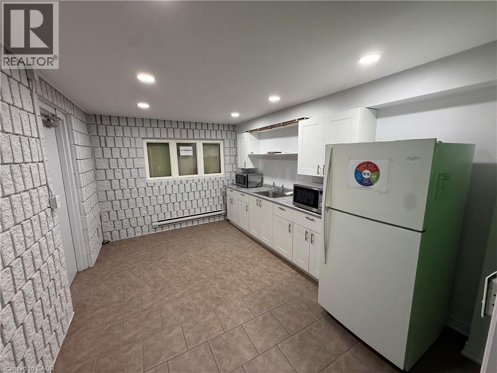 Kitchenette featuring white cabinetry, a double basin stainless steel sink, and tile flooring