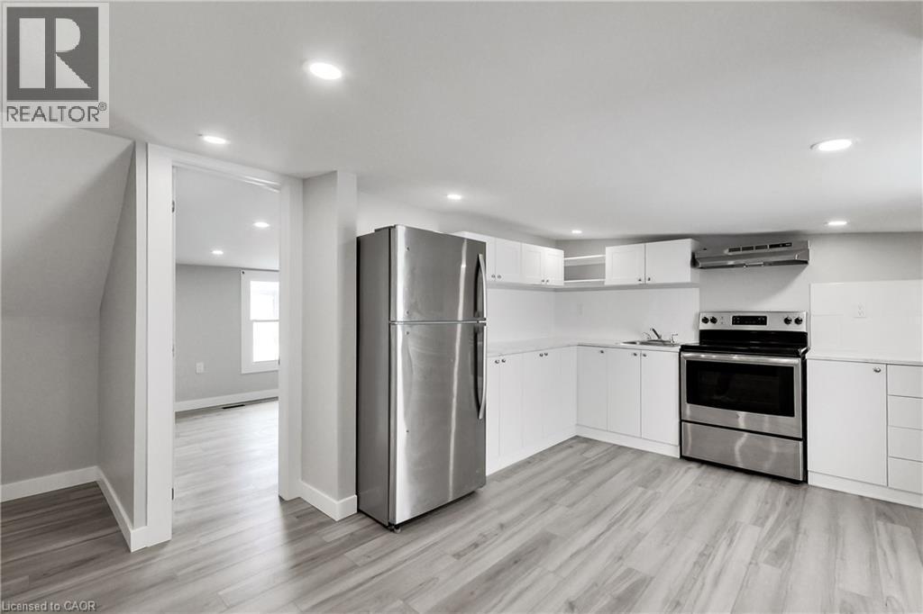 Kitchen with wood-finish flooring, white cabinetry, stainless steel appliances, and recessed lighting