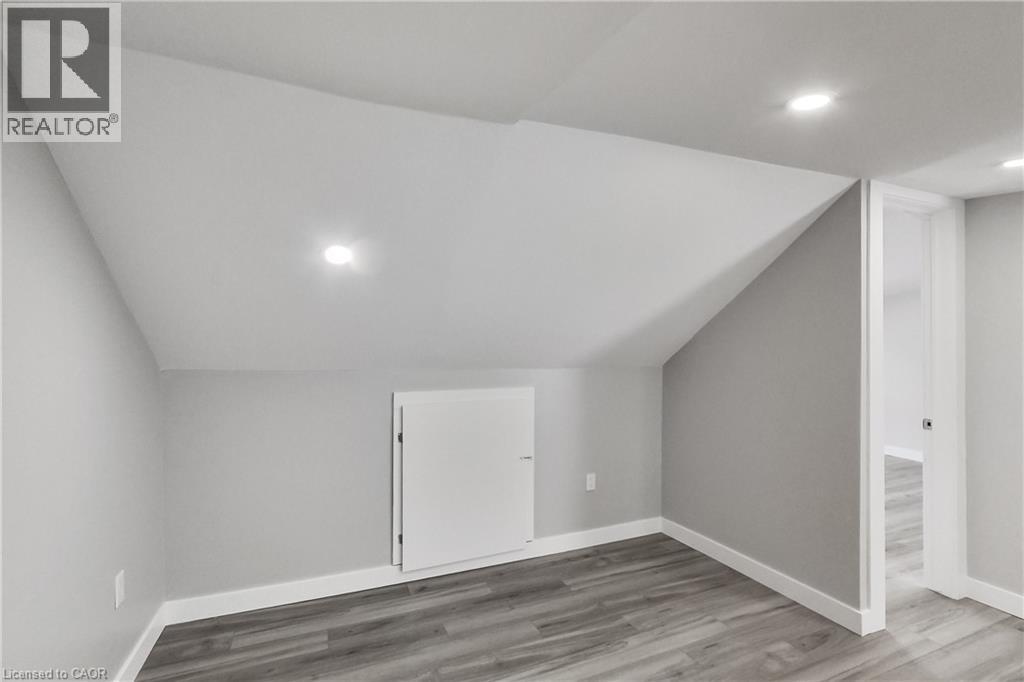 Recessed lighting, sloped ceiling, wood-finish flooring, built-in storage cabinet, and white trim