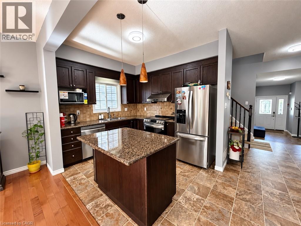 Kitchen featuring dark wood cabinetry, stainless steel appliances, a center island with a granite-style countertop, and a tiled floor