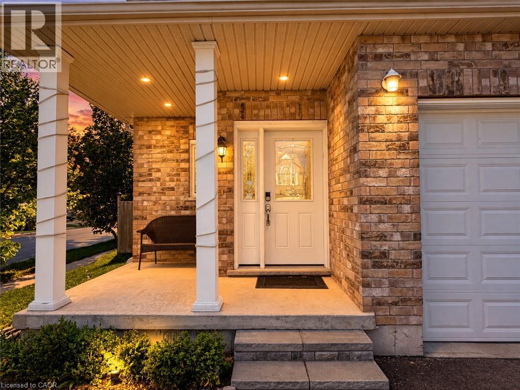 Brick exterior with a covered porch featuring recessed lighting, a decorative entry door with sidelights, and a paneled garage door