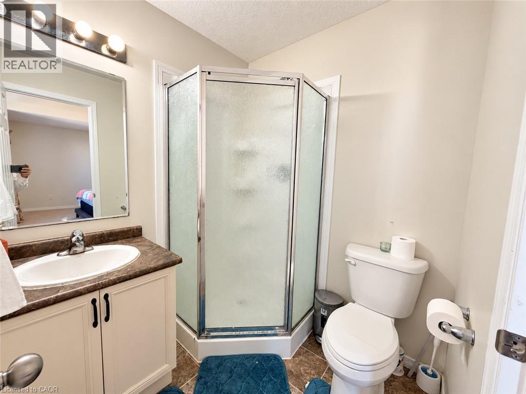 Bathroom featuring a corner shower enclosure, single vanity with an integrated sink, and a two-piece toilet