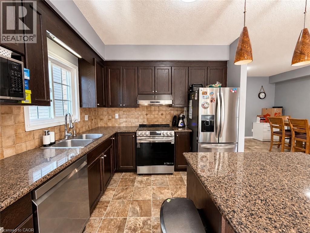 Kitchen featuring dark wood cabinetry, stainless steel appliances, speckled countertops, and a tiled backsplash