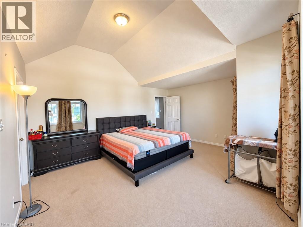 Vaulted ceilings with a ceiling-mounted light fixture, light-toned wall paint, and plush carpeting