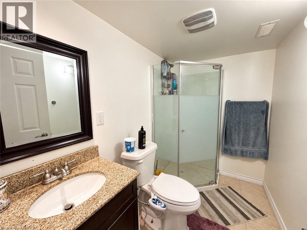 Bathroom featuring a granite countertop vanity with an undermount sink, a framed mirror, a glass-enclosed shower with frosted panels, and tile flooring