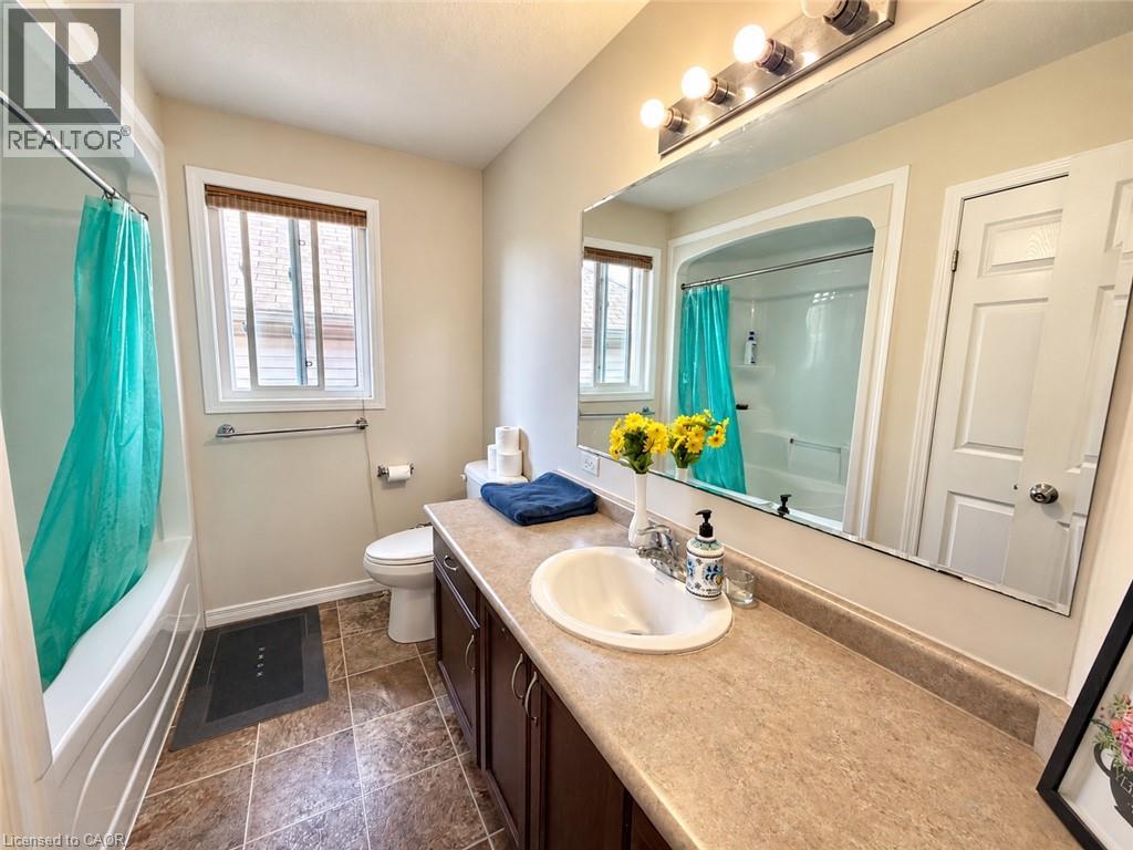 Bathroom featuring a tub/shower combination, window, vanity with an integrated sink, and a large wall-mounted mirror