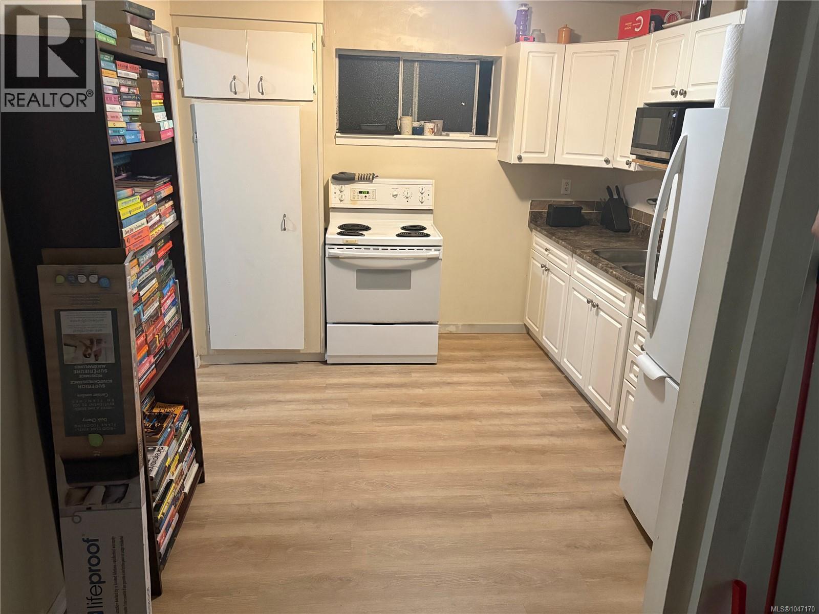 Wood-finish flooring with perimeter cabinetry and a built-in microwave