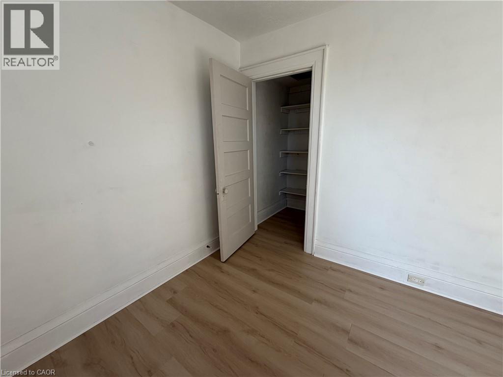 Wood-finish flooring, white walls, and a closet with built-in shelving