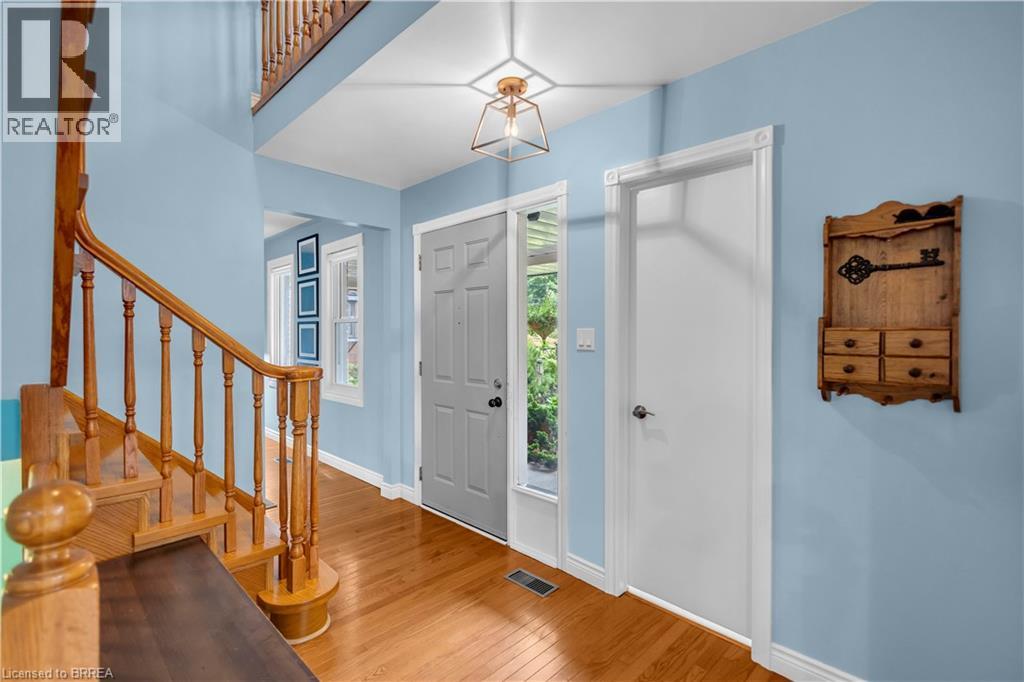 Welcoming foyer showcasing warm wood-finish flooring, soft blue walls, and abundant natural light from transom windows