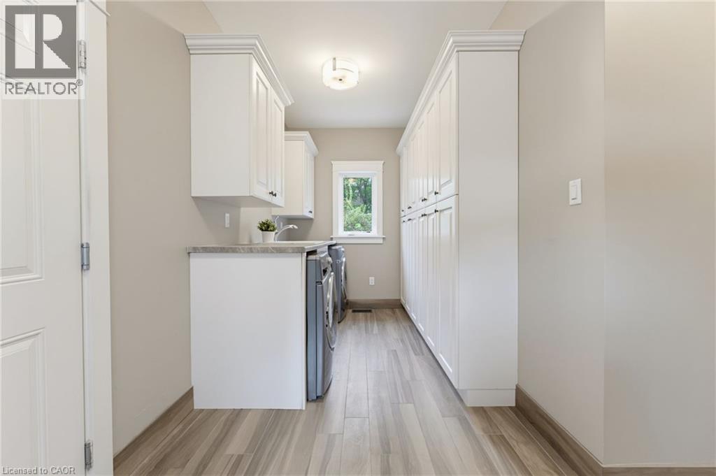 Wood-finish flooring, white cabinetry, integrated sink, window, ceiling-mounted light fixture
