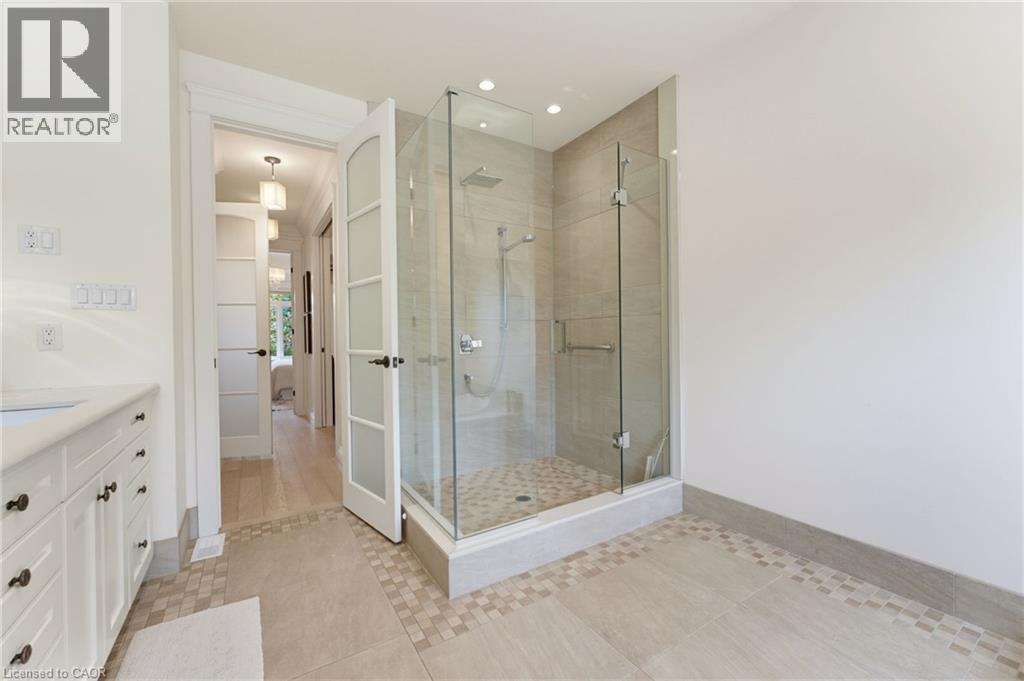 Walk-in shower with clear glass enclosure, rainfall showerhead, and mosaic tile flooring