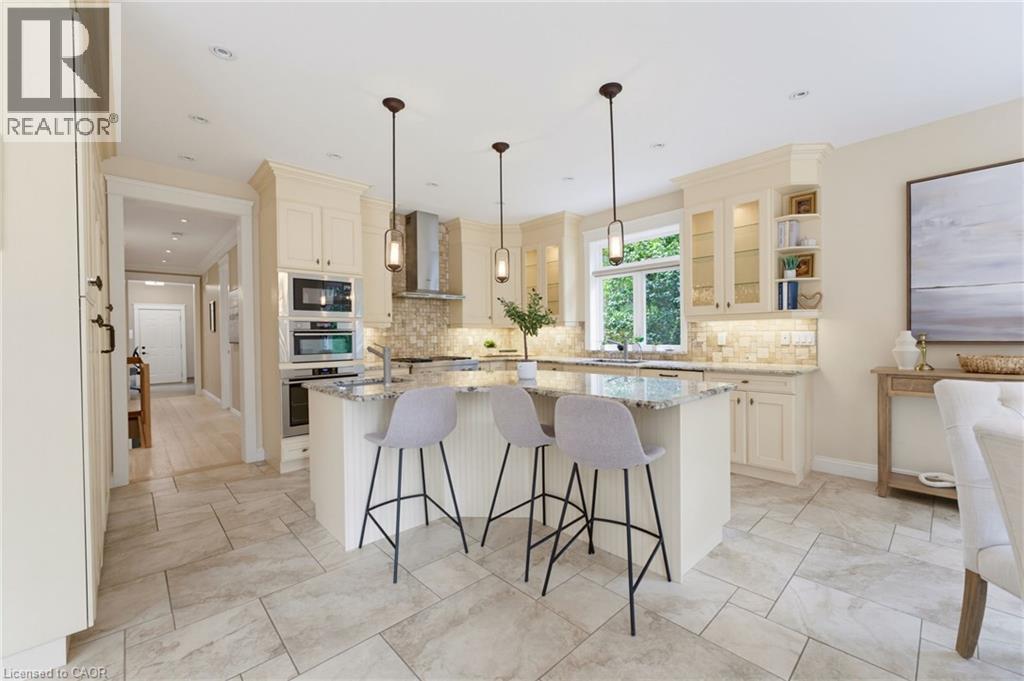 Spacious kitchen featuring an island with a stone-finish countertop, dual wall ovens, and a tile backsplash