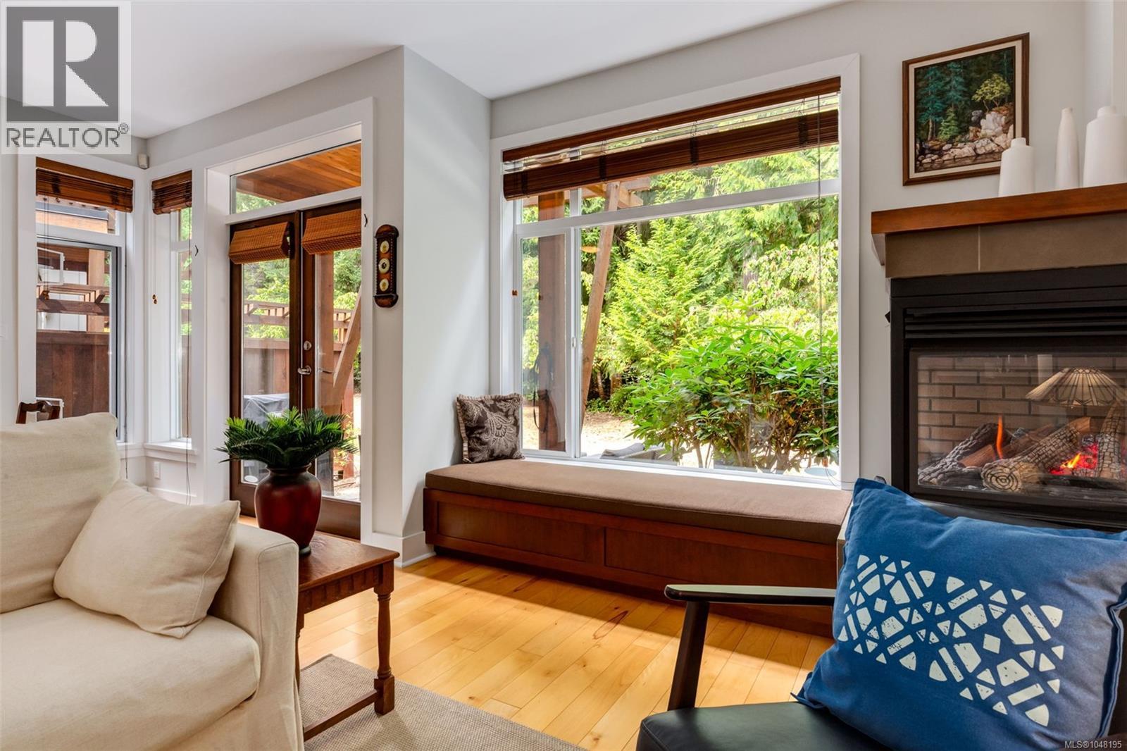 Two-sided gas fireplace, built-in window seat and large windows overlooking the surrounding greenery.