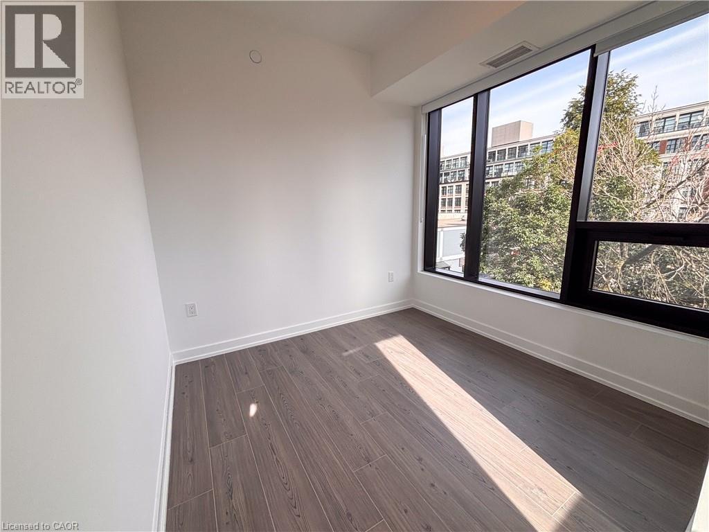 Expansive windows with black frames, wood-finish flooring, white walls, and recessed lighting
