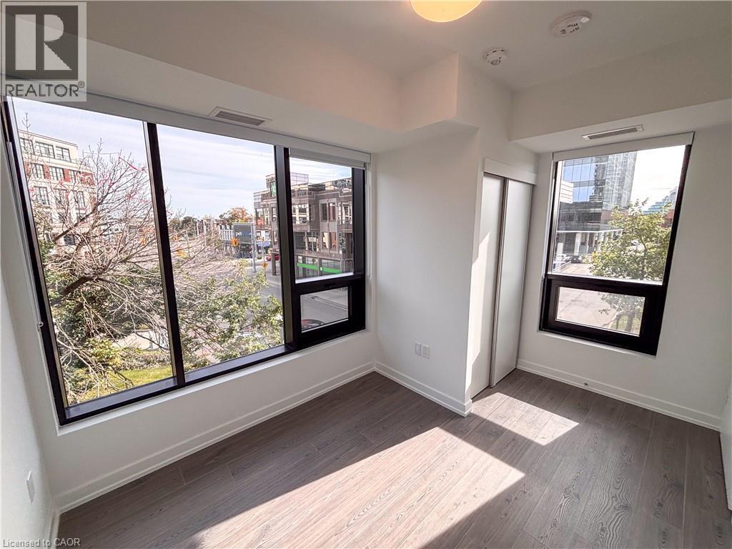 Expansive wall of windows, sleek roller shades, wood-finish flooring, white walls, and built-in closet with bifold doors