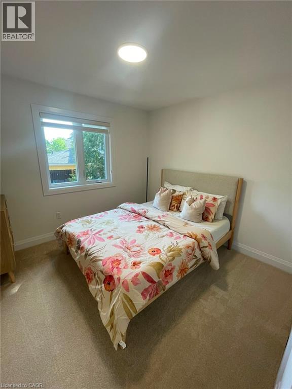Recessed ceiling lighting, white walls, carpeted flooring, and a large window