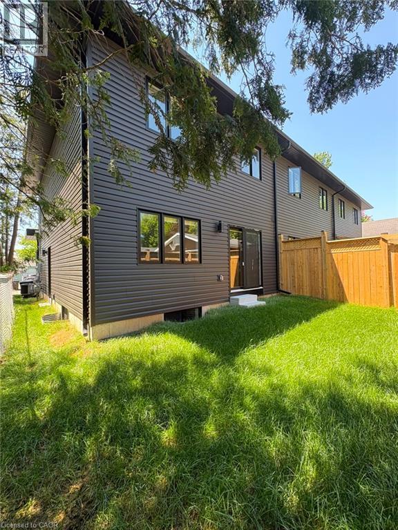 Dark-toned horizontal siding with black window frames, a rear entry door, and a wooden privacy fence