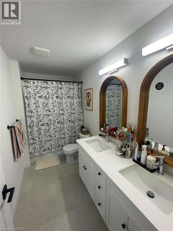 Dual vanity with integrated sinks, white cabinetry with black hardware, and two arched mirrors