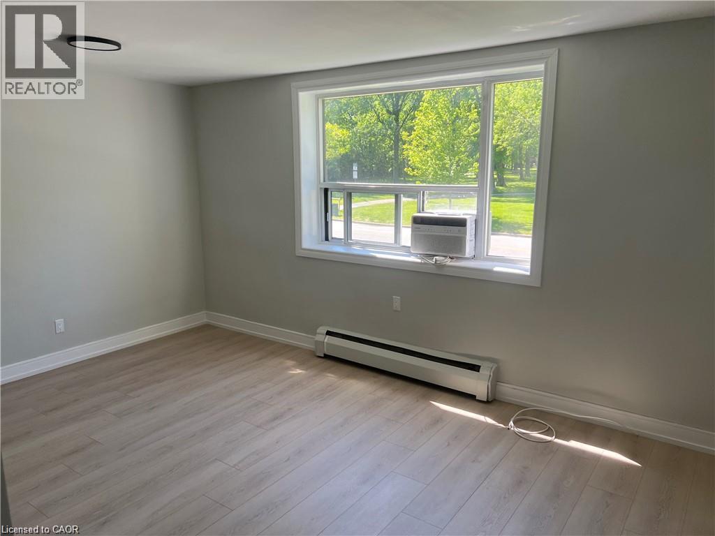 Light-toned wood-finish flooring, white trim, and a window air conditioning unit