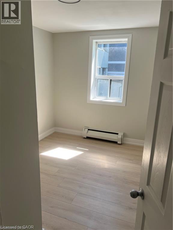 Bright interior space featuring light-toned wood-finish flooring, a white trim window, and painted walls