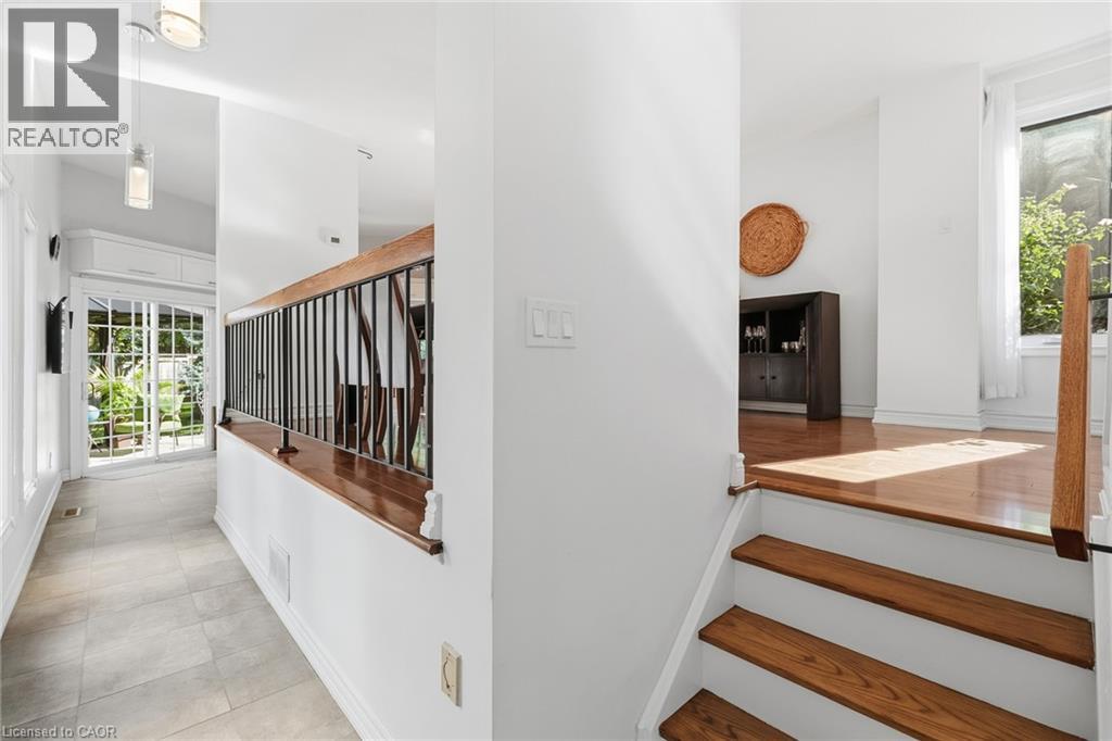 Wood flooring, tile flooring, white walls, wood staircase, and black iron balusters