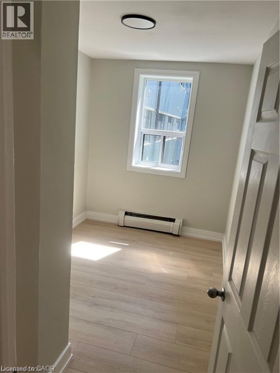 Recessed ceiling light, double-paned window, baseboard heater, wood-finish flooring, and panel door