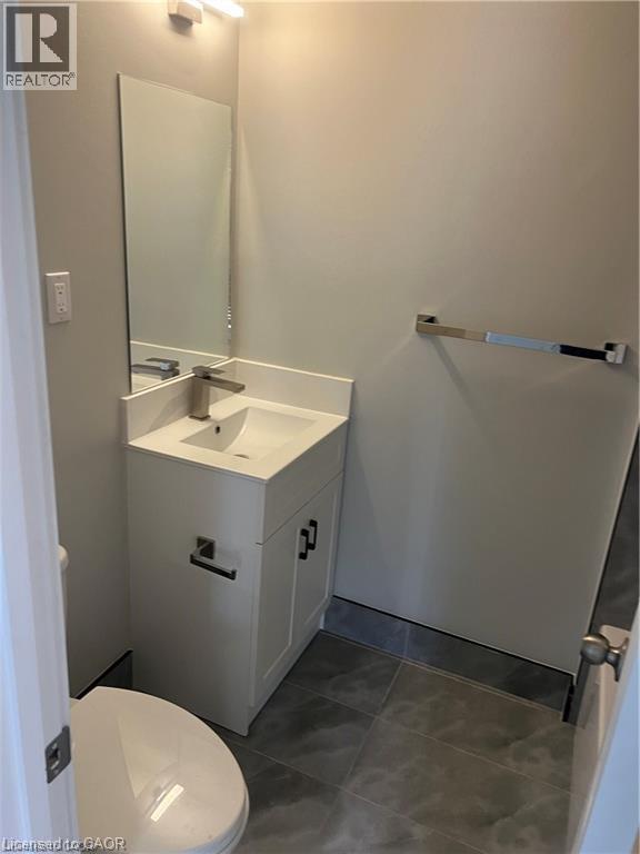Vanity with integrated sink, chrome faucet, wall-mounted mirror, and tile flooring
