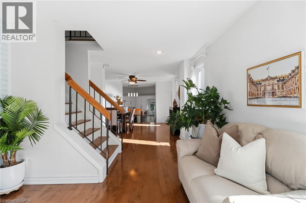 Hardwood flooring throughout, a staircase with wood handrails and black balusters, and recessed lighting