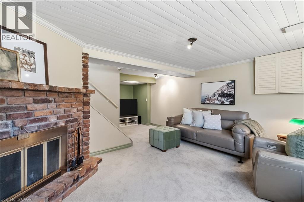 Exposed brick fireplace with a brass firebox, coffered ceiling, track lighting, and soft carpet flooring